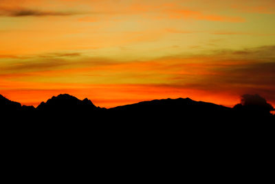 Scenic view of silhouette mountains against orange sky