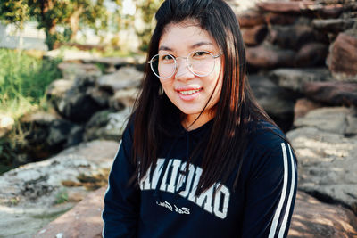 Portrait of smiling young woman standing on rock