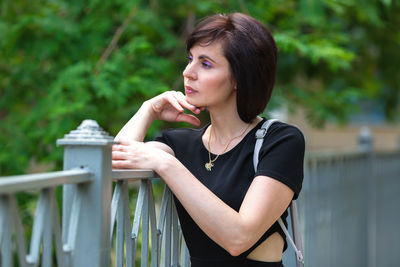 Beautiful slender middle aged brunette in a black dress on a sunny summer day.