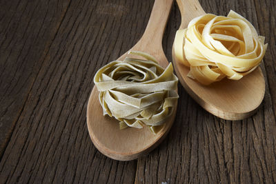 Close-up of tagliatelle pasta in wooden spoons on table