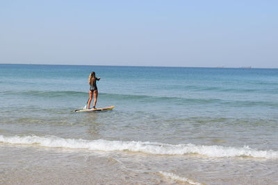 Man surfing in sea against clear sky