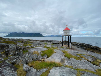 Lighthouse by sea against sky