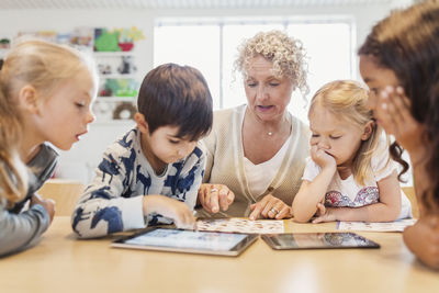 Senior teacher and children with charts and digital tablets