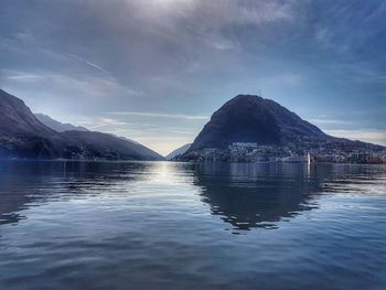 Scenic view of sea by mountains against sky