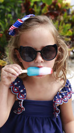 Toddler girl with blue swimsuit eating a popsicle in red, white and blue colors