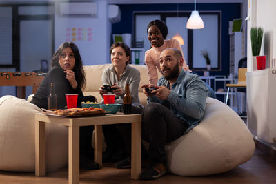 Excited friends playing video game at office