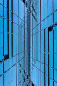 Low angle view of glass building against blue sky