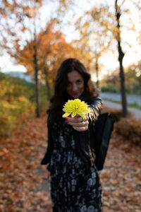 Beautiful woman standing by tree trunk during autumn