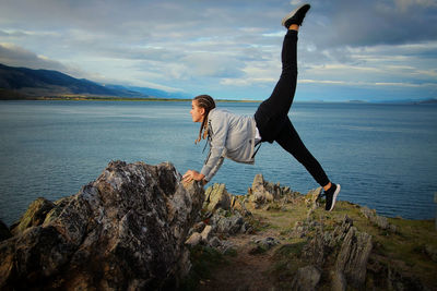 Full length of girl exercising against sea and sky