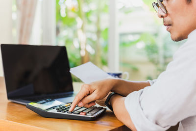 Midsection of man using laptop on table