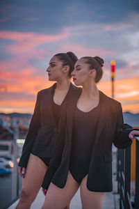 Young couple looking away against sky during sunset