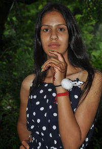 Portrait of a beautiful young girl looking at camera and posing with her hand on her chin and hip