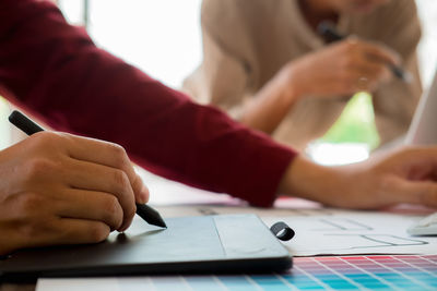 Cropped hands of colleagues discussing on desk in office