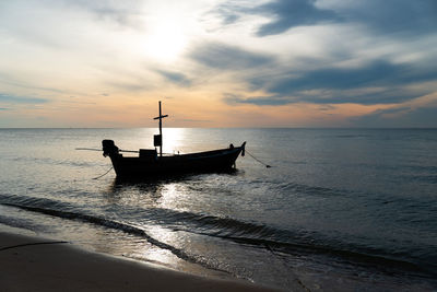 Silhouette of small fishing boat in the sea at sunrise