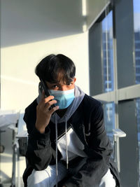 A guy wearing a facemask while talking on the phone