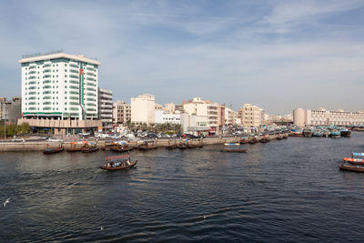 Boats in sea by buildings against sky