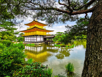 Traditional building by lake against sky