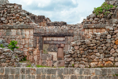 Stone wall of old building against cloudy sky