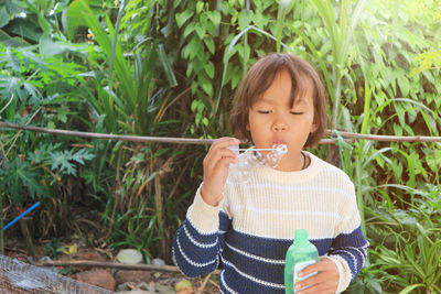 Cute girl holding bubble wand while standing outdoors