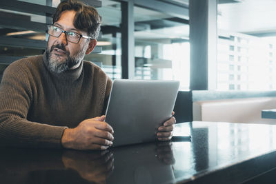 Man using laptop while sitting on table