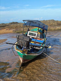 Boat moored on beach against sky