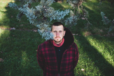 Portrait of young man standing against trees