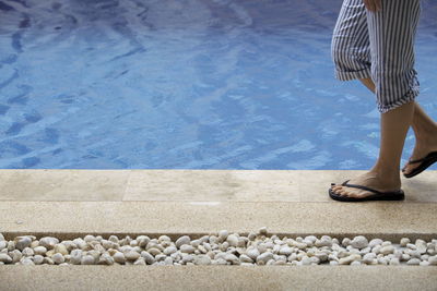 Low section of woman walking at poolside