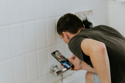 A young man installs a faucet in the bathroom via video link.