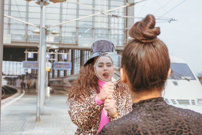 Woman showing mirror to friend in city