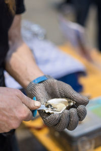 Midsection of man holding oyster 