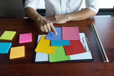 Low section of man holding paper with text on table