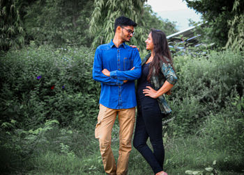 Young couple standing by plants at park