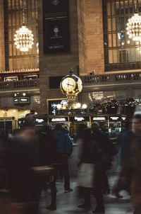 People walking on illuminated street in city