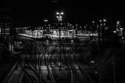 Train on illuminated railroad tracks against sky at night