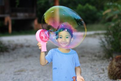 Portrait of cute girl blowing bubble in park