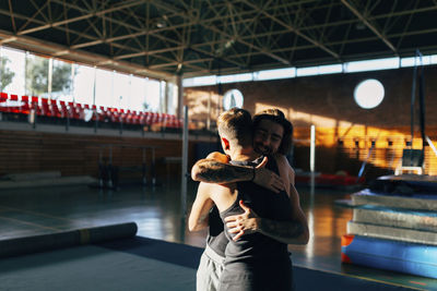 Happy friends embracing while standing at gym