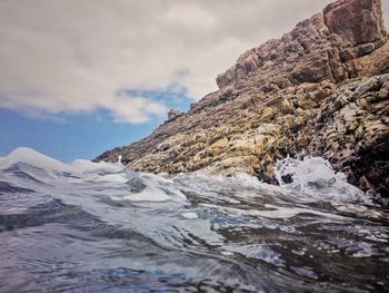 Rock formation in sea against sky