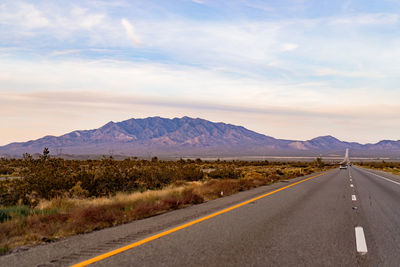 Road by mountains against sky