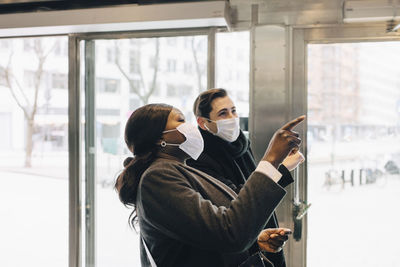 Male and female colleagues pointing while standing in store during pandemic