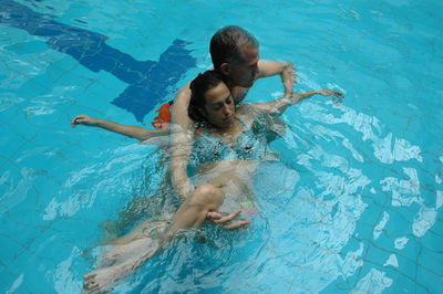 Man helping woman in swimming pool