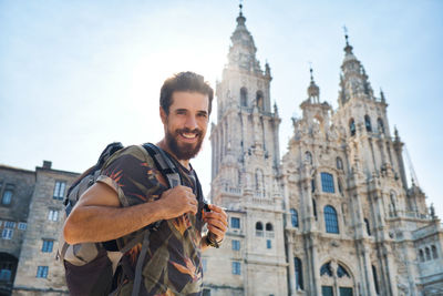 Portrait of smiling man standing against cathedral in city