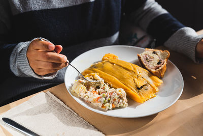 Woman eating traditional venezuelan christmas dish with hallacas, pan de jamon 
