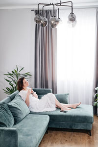 Low section of woman sitting on bed at home