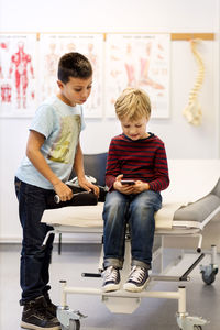 Brothers using smart phone at examination table in orthopedic clinic
