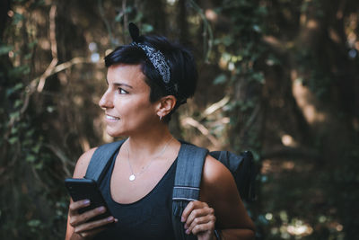 Woman using smart phone while standing in forest