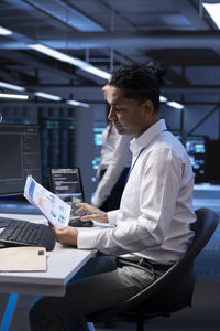 Side view of businessman using laptop on table