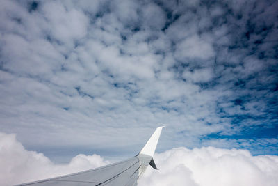Airplane wing against cloudy sky