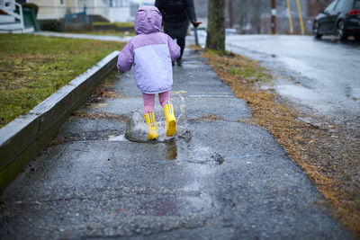 A little girl having fun splashing in puddles on a rainy day.