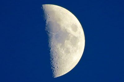 Low angle view of moon against clear blue sky