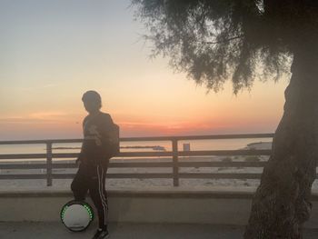 Silhouette man with bicycle by sea against sky during sunset